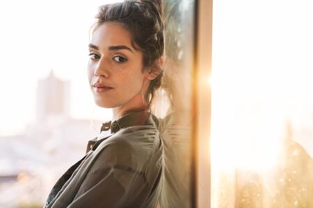 files/133286476-imagen-de-una-encantadora-mujer-morena-mirando-la-camara-y-parada-sobre-una-puerta-de-vidrio.jpg